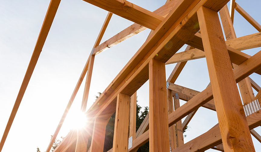 Sun shines through the wood frame of a home under construction