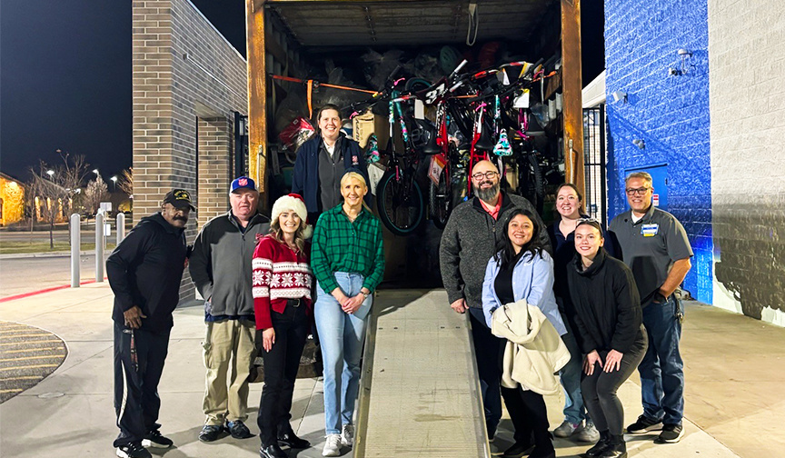 Representatives from Cyprus Credit Union and The Salvation Army stand in front of a truck loaded with holiday gifts for the Angel Tree program.