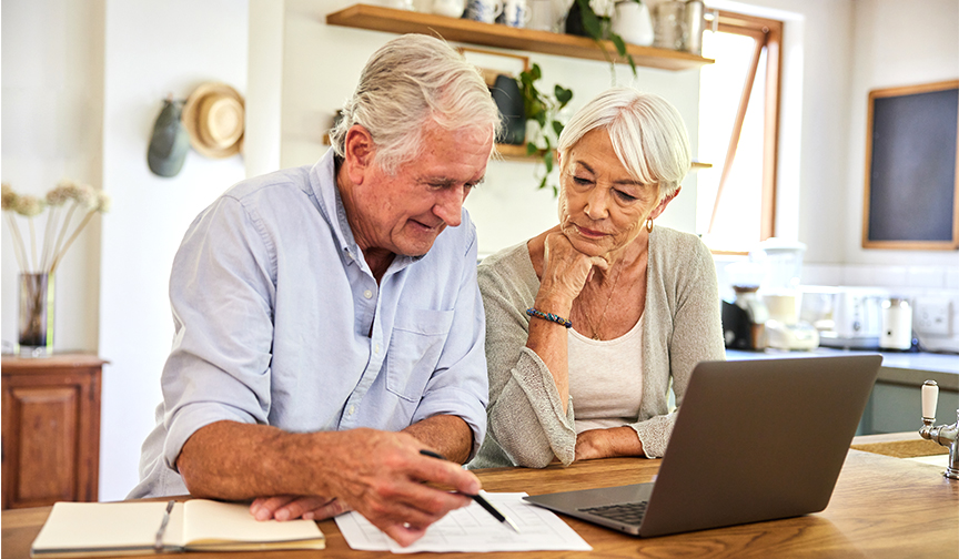 older couple in front of laptop taking notes