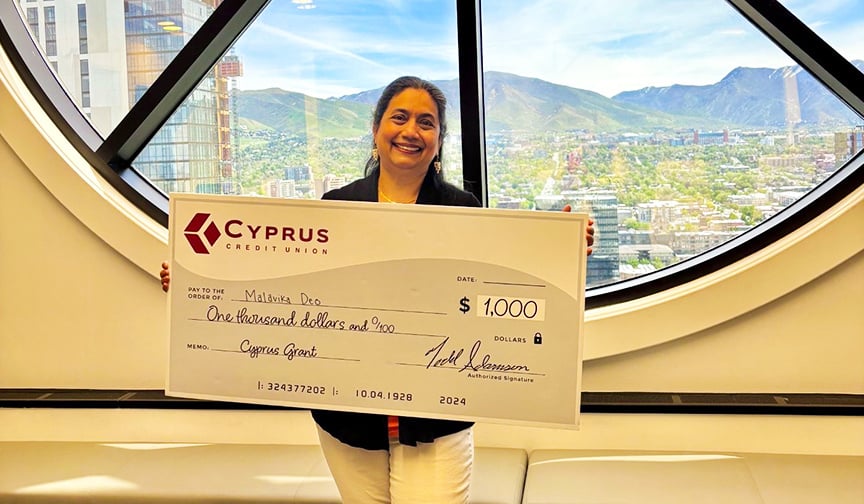 Malavika Deo, owner of Deolicious LLC in Utah, stands with a $1,000 check from Cyprus Credit Union.