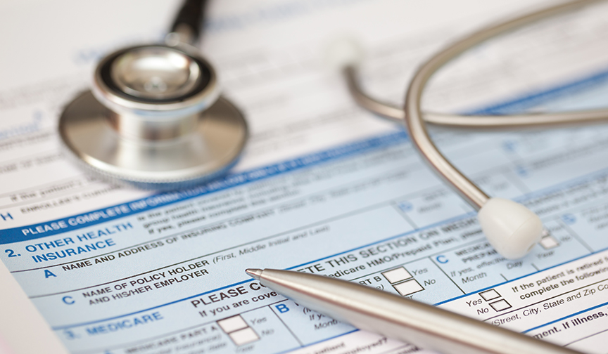 A stethoscope rests on top of a health insurance form