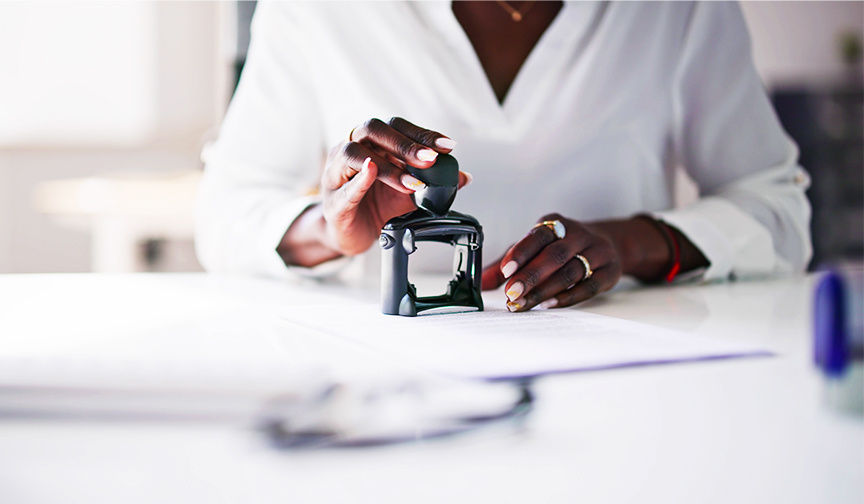 person with stamp stamping on paperwork