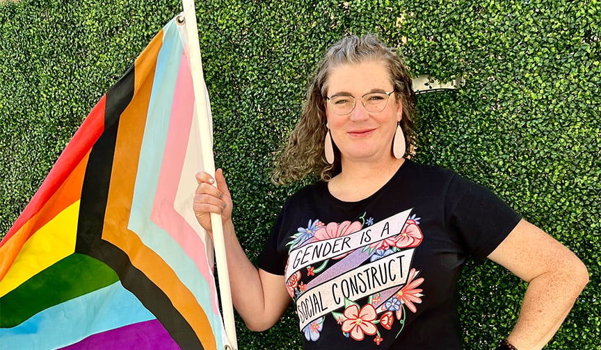 Project Rainbow Executive Director Jacey Thornton poses with a rainbow pride flag