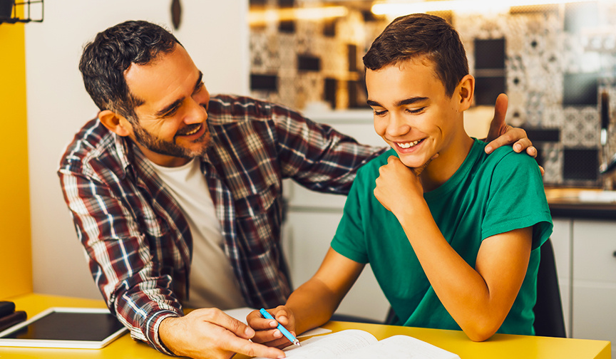 father and son smiling while sitting and reading