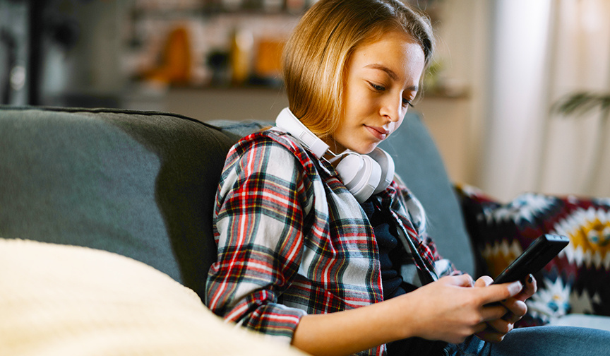 teen using phone and wearing headphones