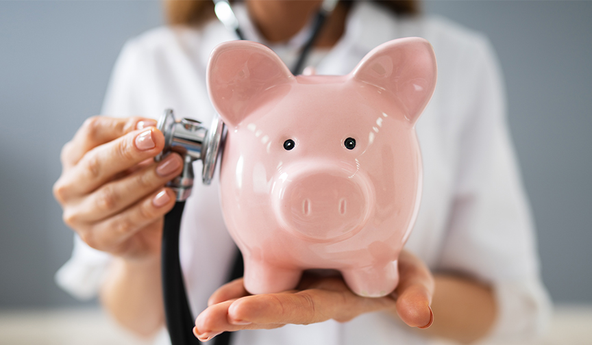 A doctor holds a stethoscope up to a pink piggy bank