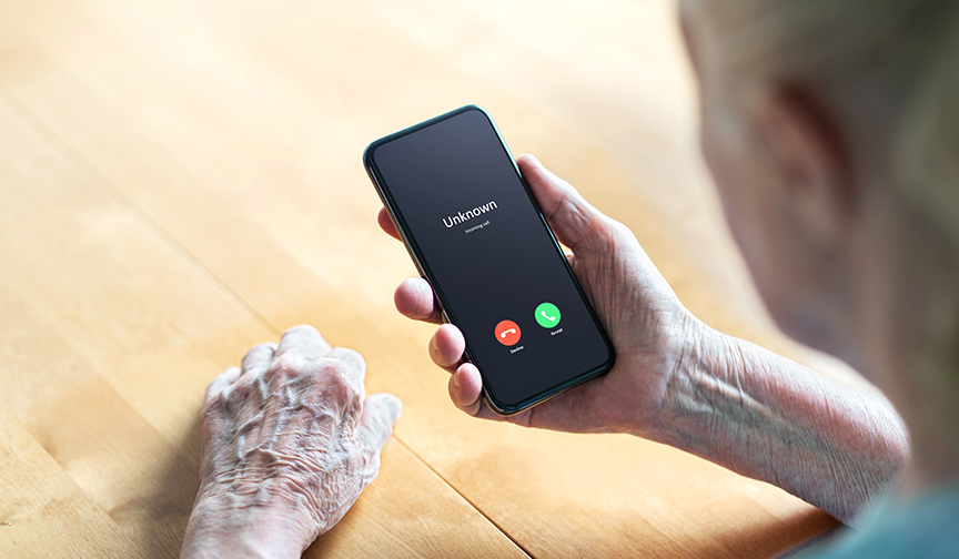 An elderly woman holds her smart phone as she gets a call from an unknown number