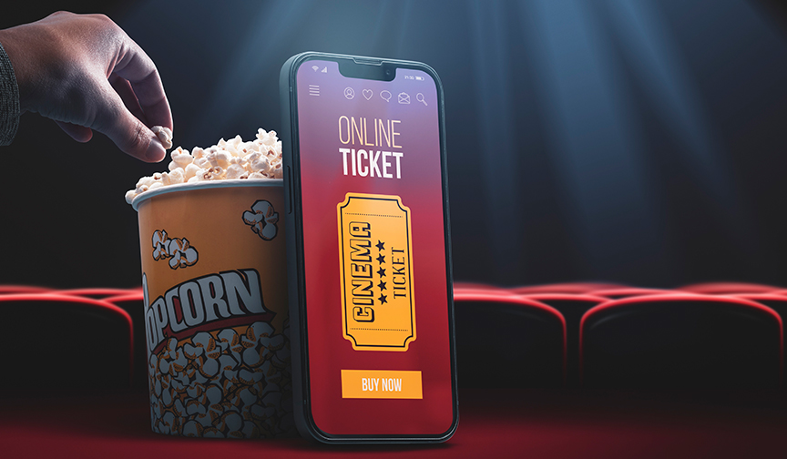 A popcorn container sits next to a cell phone screen displaying an online movie ticket